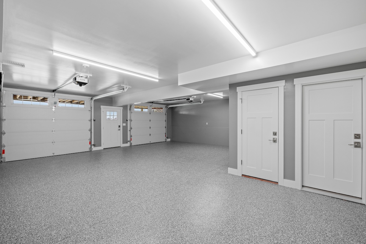 Interior view of an empty garage with a metallic surface floor and lighting