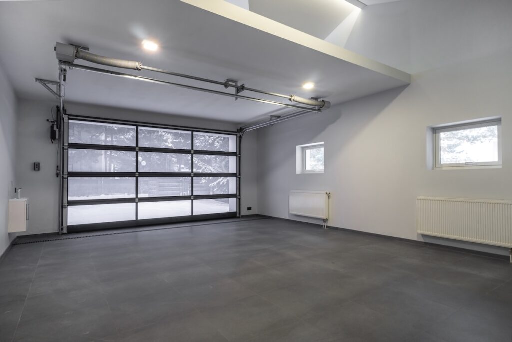best garage floor coating A bright and spacious garage features large glass doors letting in natural light. The clean floor and minimalist design create an inviting atmosphere, ideal for storage or workspace.