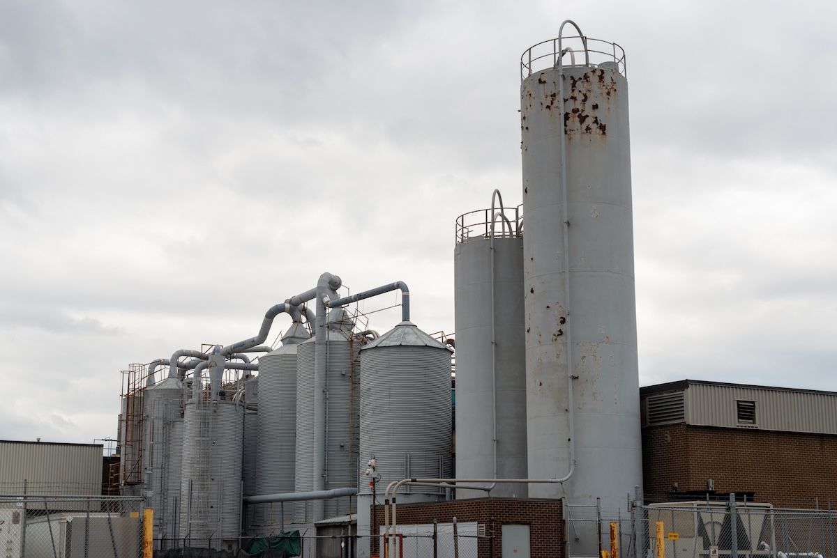 industrial silo painting process Large grey metal silos at a paint manufacturing plant. The storage tanks range in height and size. The pressure tanks are filled with chemicals for the production of paint.