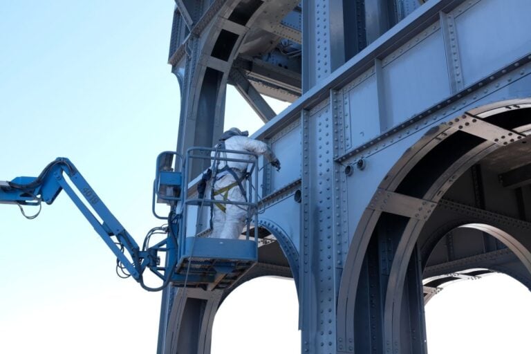 fire resistant paint for metal McLean Company worker painting metal big structure blue paint