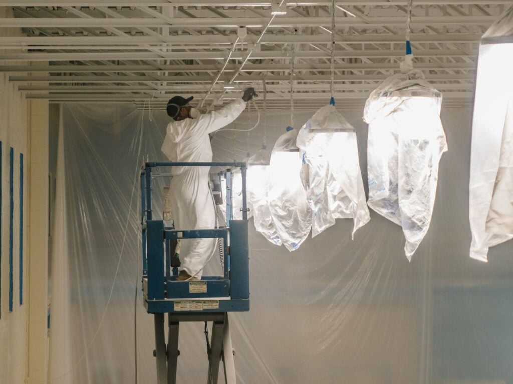 food grade paint McLean Company worker cover lights with plastic bags to prepare for painting