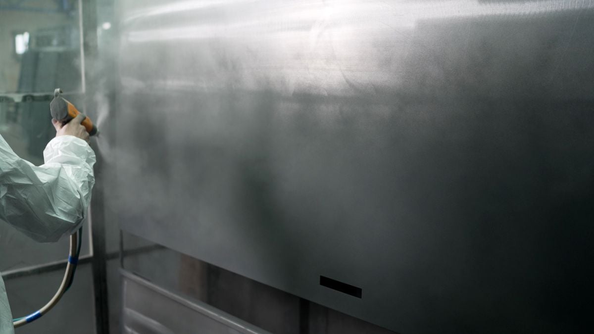 heat resistant paint worker spraying black paint into metal surface with spray gun