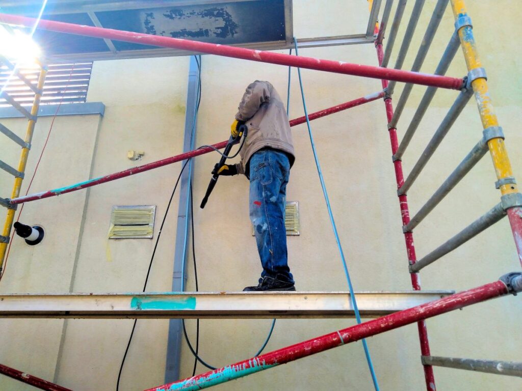how to remove spray paint from concrete worker standing on platform preparing wall with hydraulic hose