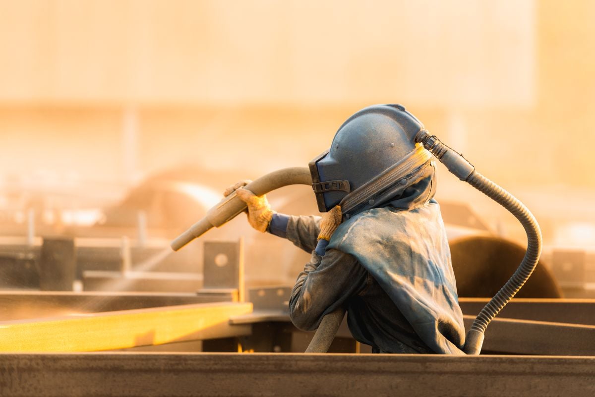 sandblasting worker using security helmet and especial blasting hose