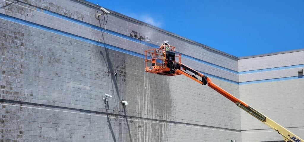 surface preparation for painting McLean Company worker using hydraulic hose cleaning wall