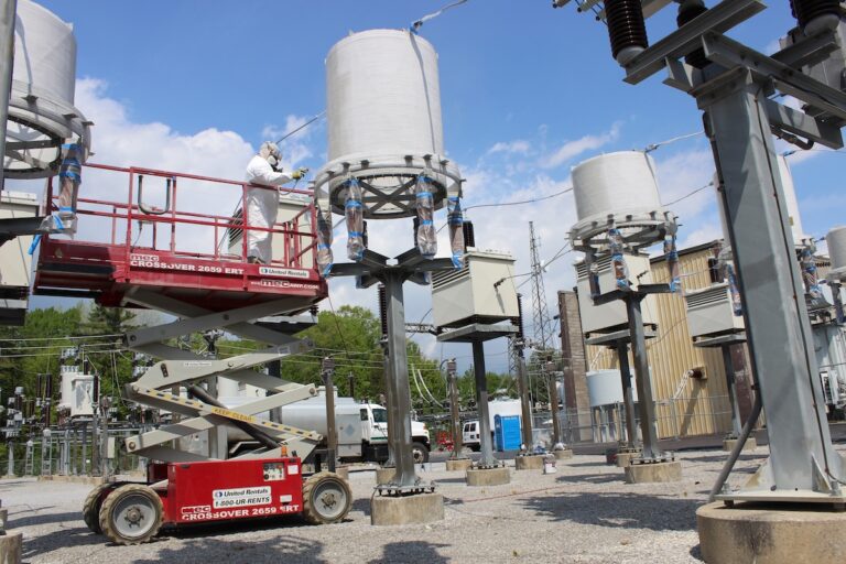 Worker on lift near electrical equipment doing industrial painting