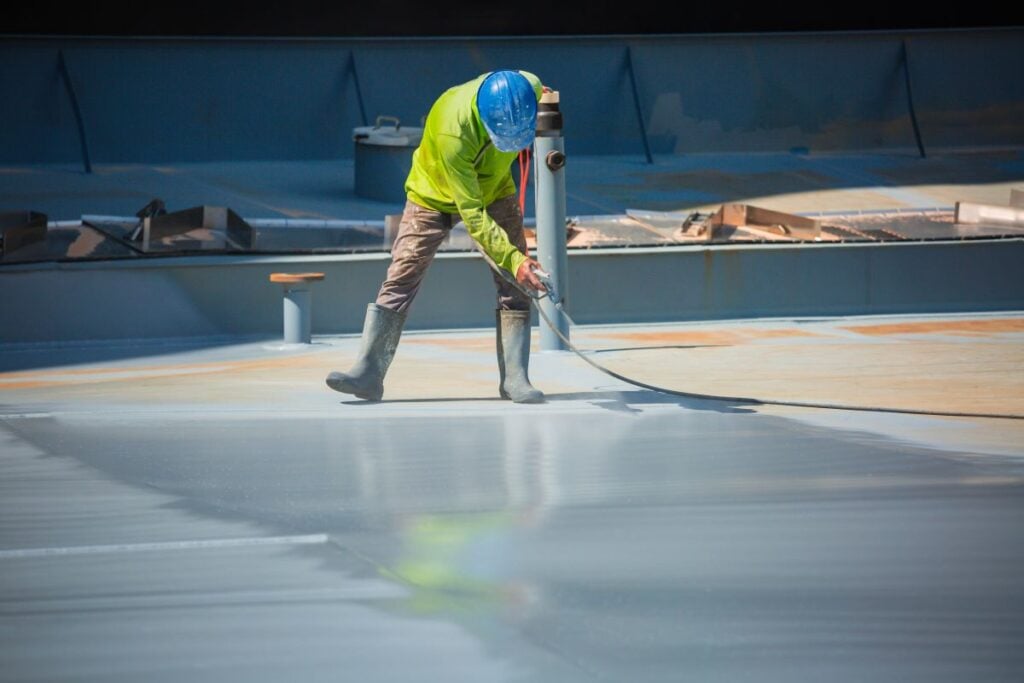 A male worker holding an industrial spray gun used for roof