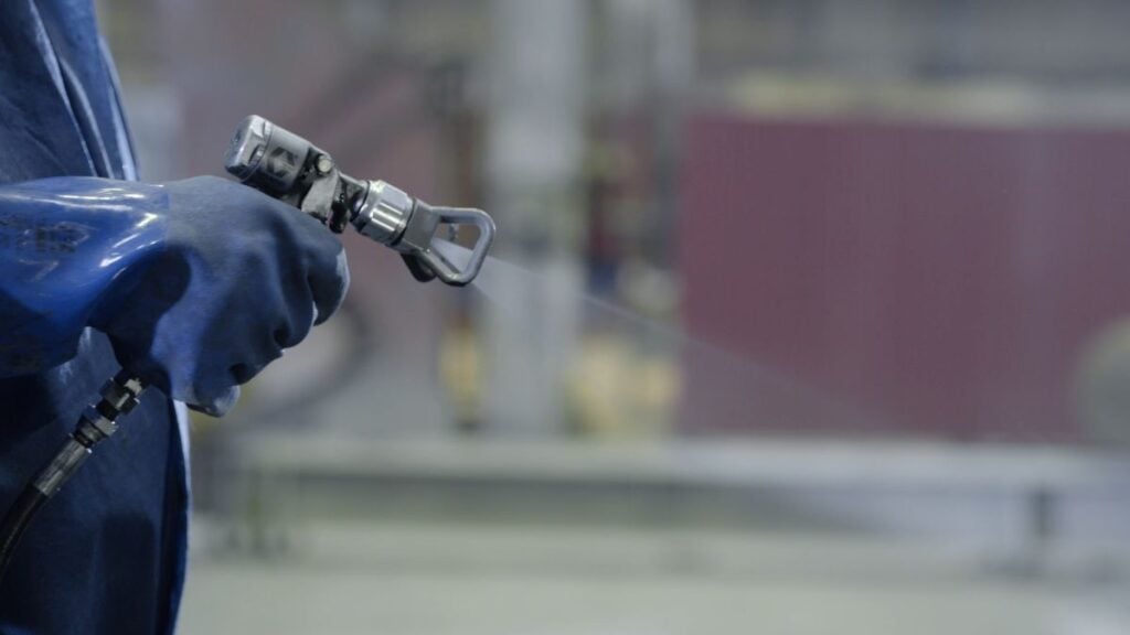 Arm hand holding industrial size spray gun used for industrial painting and coating
