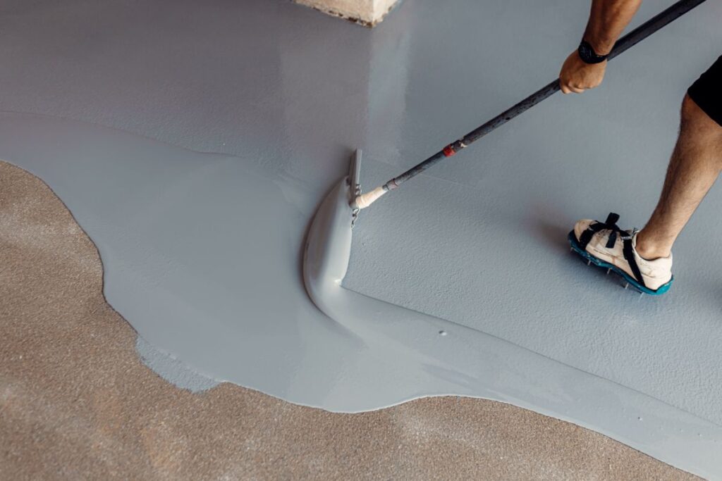 Construction worker applying epoxy resin flooring using a squeegee