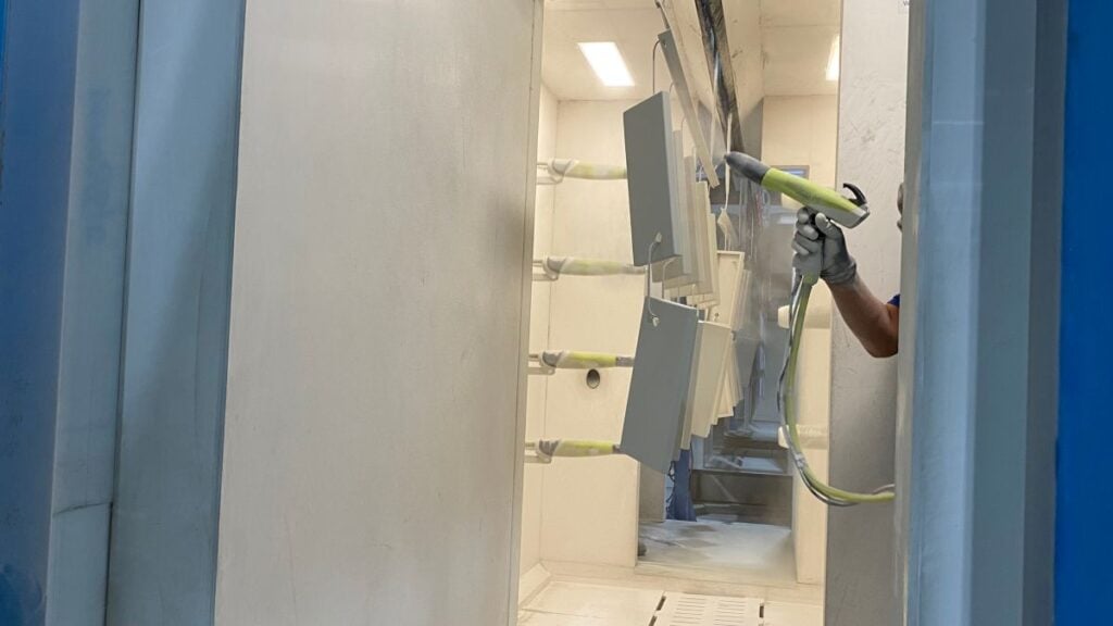 Industrial worker using an electrostatic spray gun for powder coating metal parts