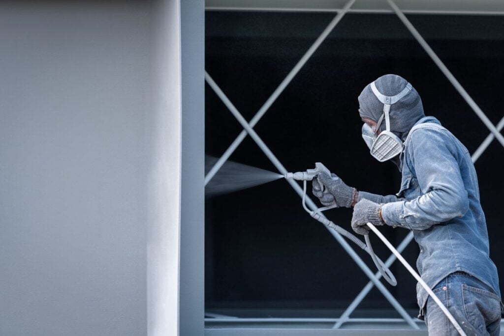 Worker painting on steel wall surface by airless spray gun for protection rust and corrosion