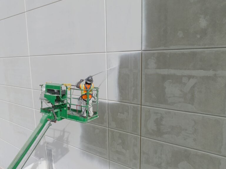 Worker painting the exterior of a tilt-up commercial warehouse