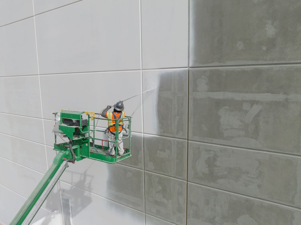 Worker painting the exterior of a tilt-up commercial warehouse