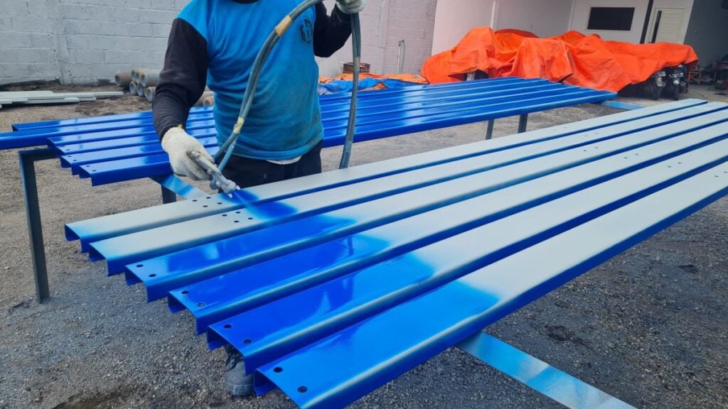 construction worker is painting steel construction with spray paint tool 