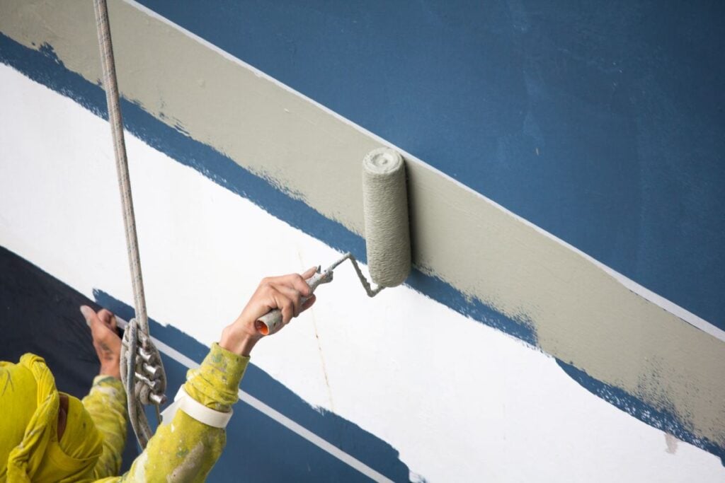 painters hanging on roll, painting color on building wall