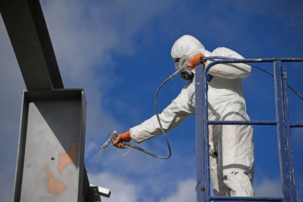 worker spray painting a beam