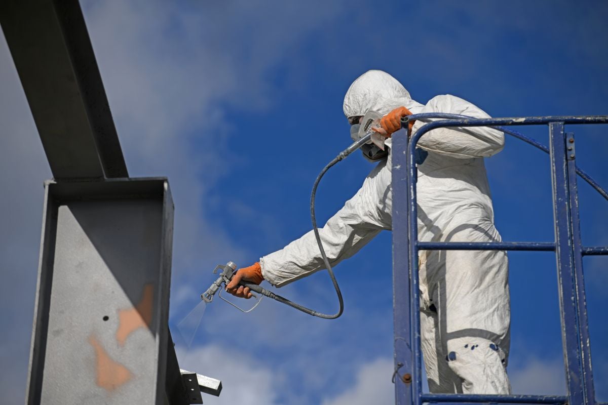 worker spray painting a beam