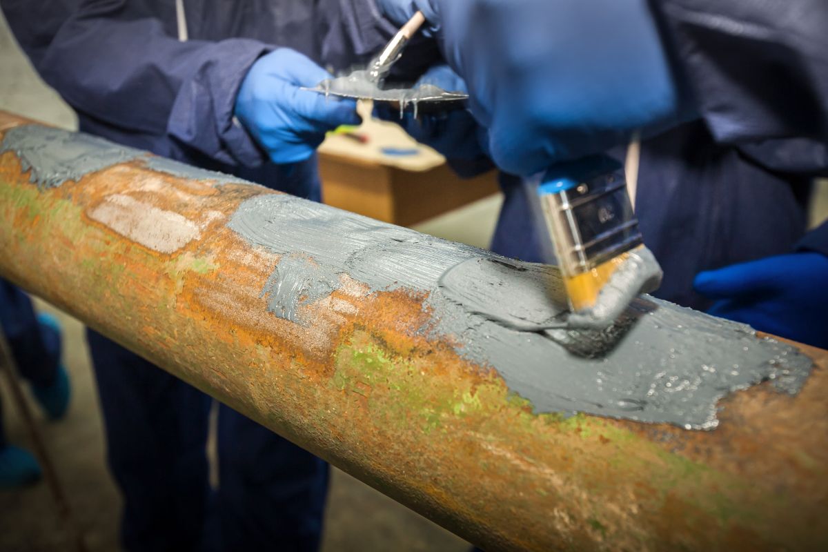 rust inhibitor worker using epoxy on rusty pipe