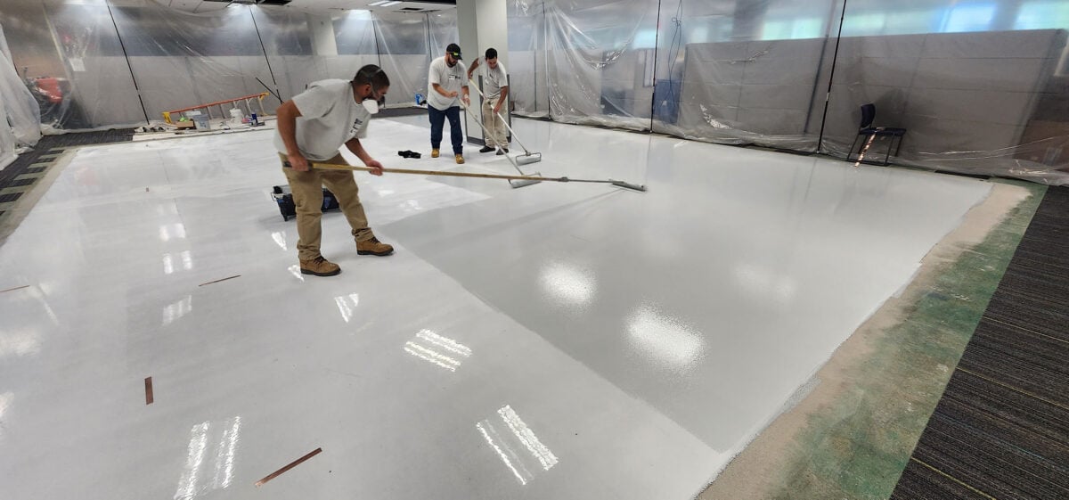 garage floor epoxy colors workers applying white coating on the floor