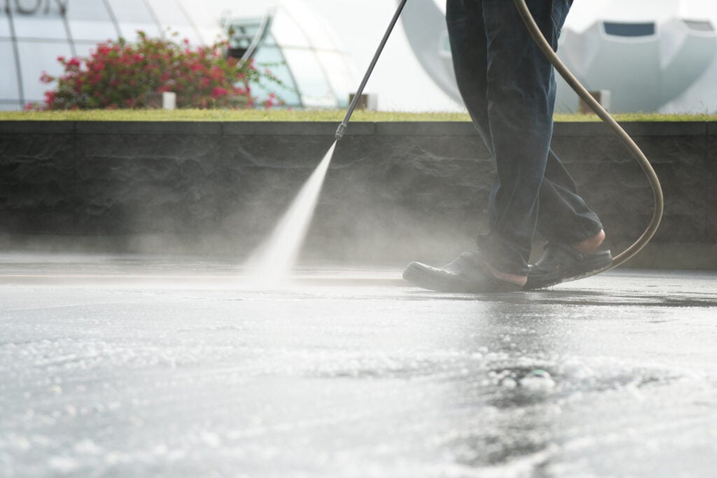 commercial pressure washing man holding hose cleaning the floor