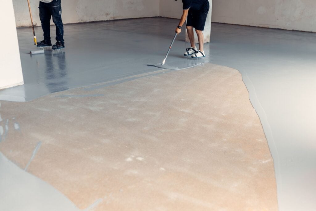 concrete epoxy floor man applying resin on the floor