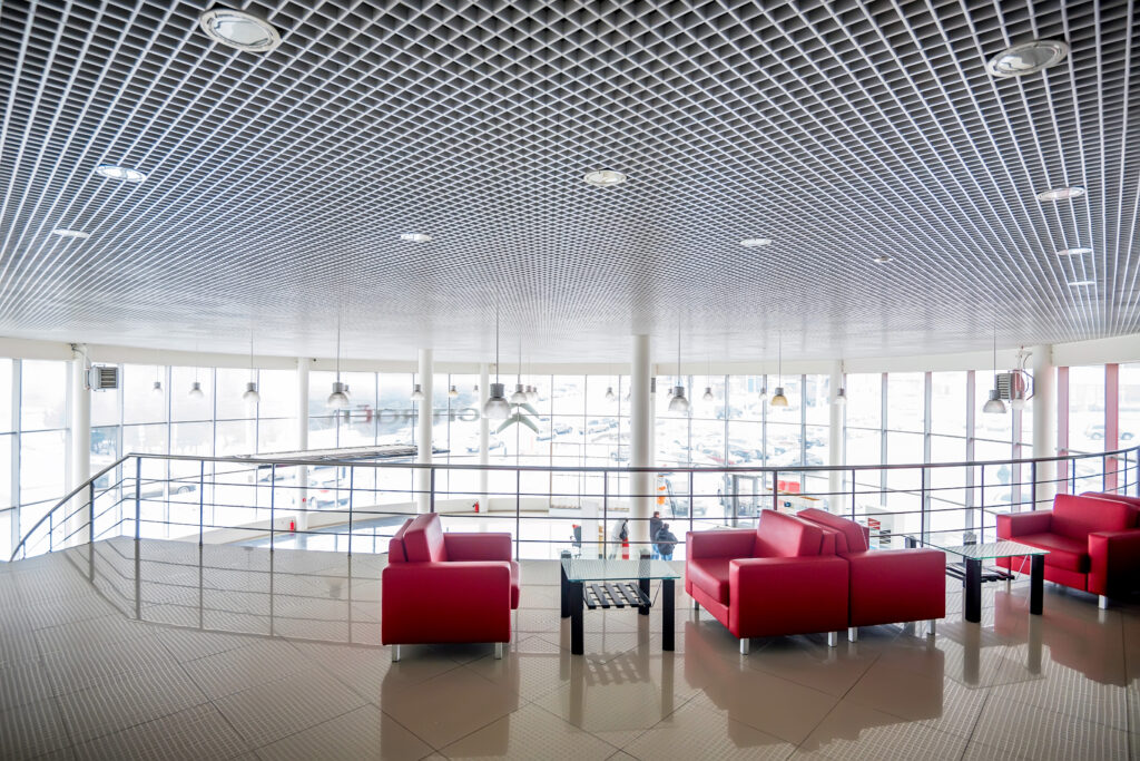 car dealership flooring Interior of modern waiting area in car showroom with red sofas and glass tables