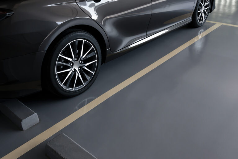 modern car in parking lot, anti slip coating floor for safety, car parked in the right position in modern building carpark area, image with copy space for banner background, diagonal composition