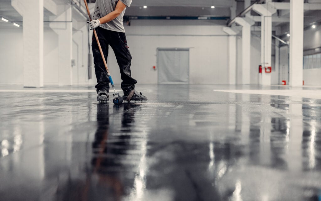 manufacturing facility flooring Industrial hall is covered in black epxy resin by a worker