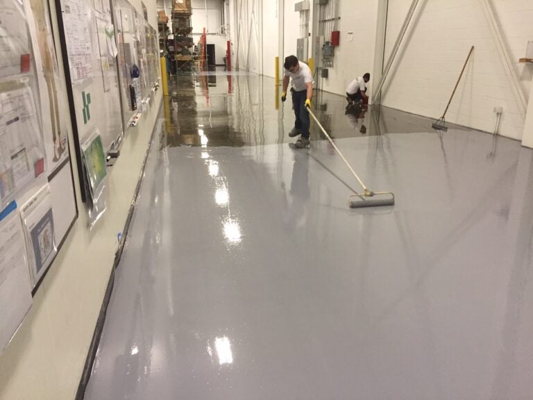 Worker applies grey coating on the floor