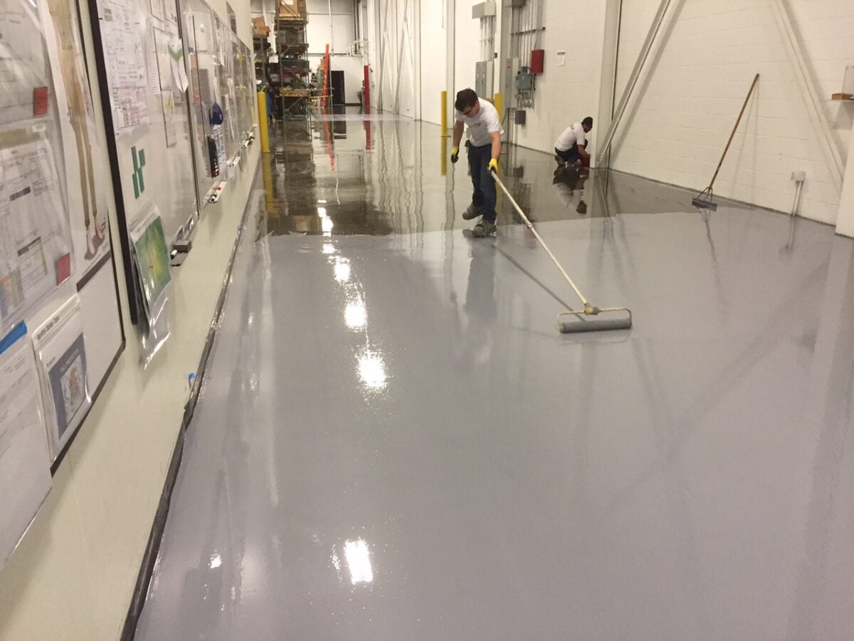Worker applies grey coating on the floor