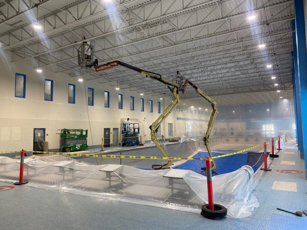 high ceiling and dryfall painting contractor man painting ceiling inside warehouse