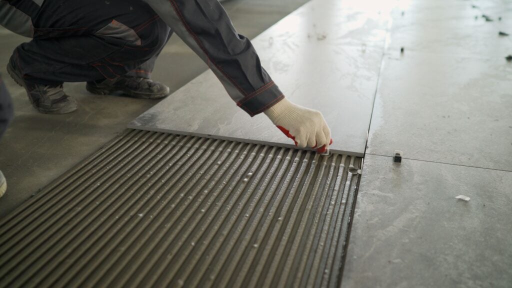 Workers lay large tiles on the floor. Installing a large ceramic tile.
