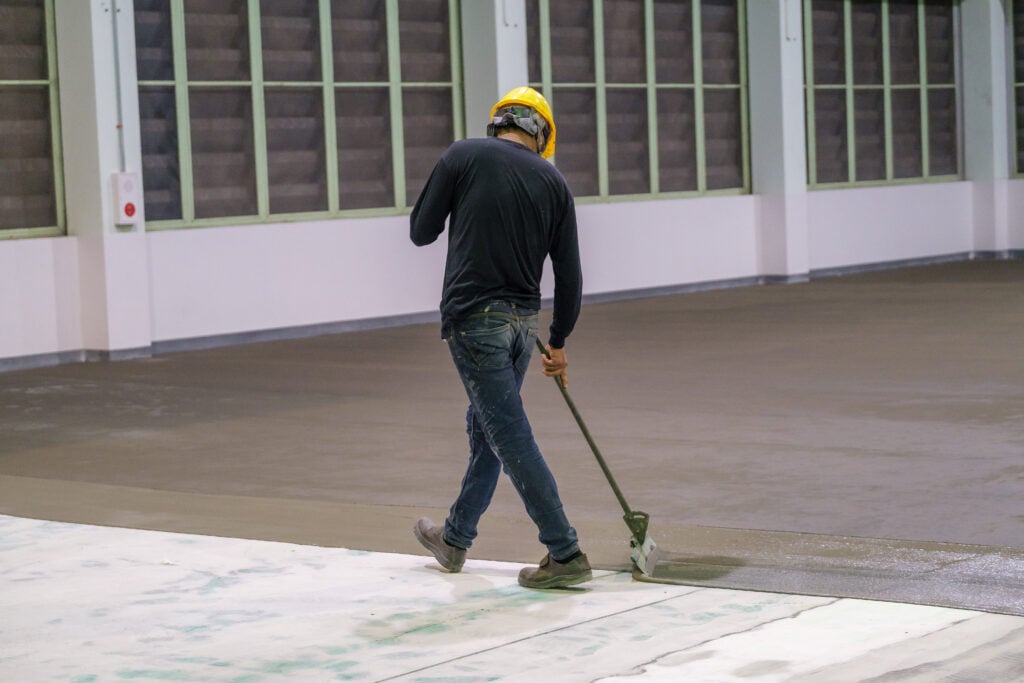 Construction worker using trowel spreading moisture blocking epoxy primer for Self-leveling method of epoxy floor finishing work self-leveling underlayment